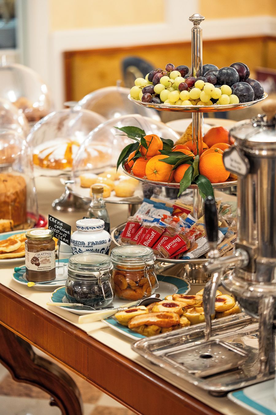Una mesa de buffet con diversas opciones de comida, incluyendo frutas, pasteles y salsas.