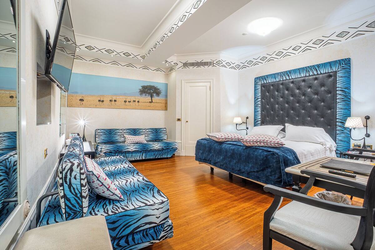 Une chambre à coucher avec un lit, un canapé, une chaise, un bureau et un téléviseur.