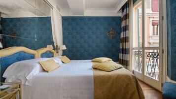 Habitación de hotel con una cama grande, una mesita de noche, un espejo y una ventana con vistas al exterior.
