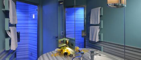 A bathroom with a marble sink, a mirror, and two towel racks with white towels.