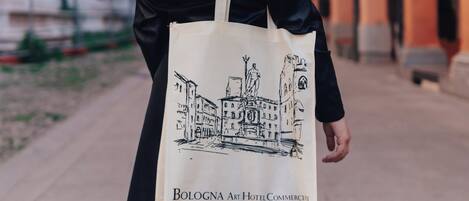 A woman walking on a street with a bag labeled "Bologna Art Hotel Commerce".