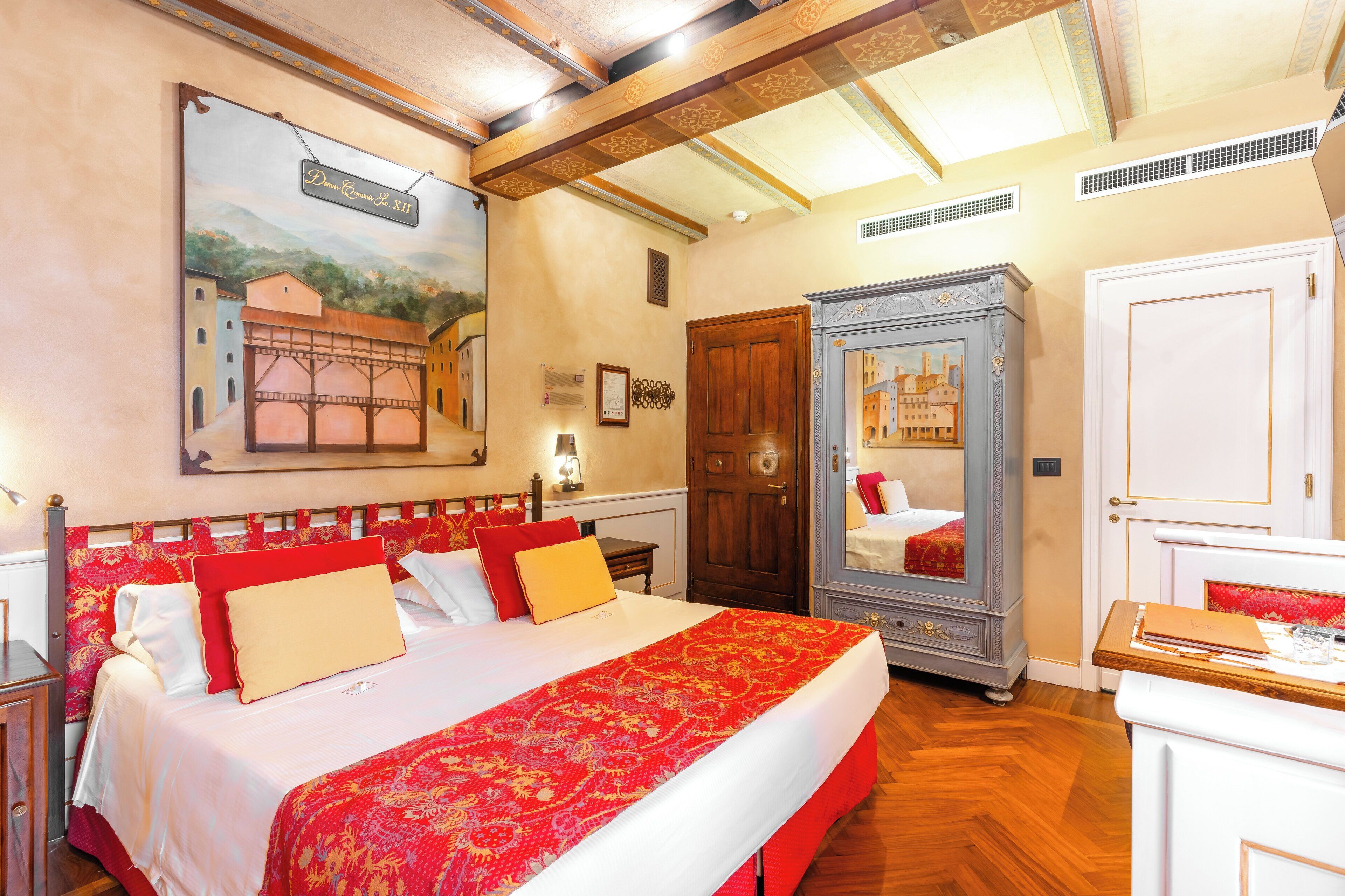 Een hotelkamer met een groot bed, een houten garderobe, een spiegel en een schilderij aan de muur.