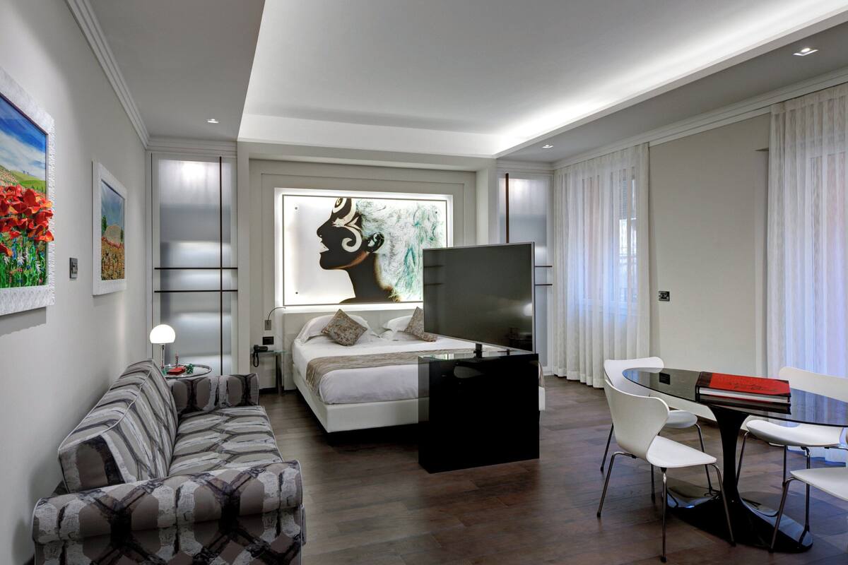 Une chambre d’hôtel moderne équipée d’un lit, d’un canapé, d’un bureau et d’une télévision.