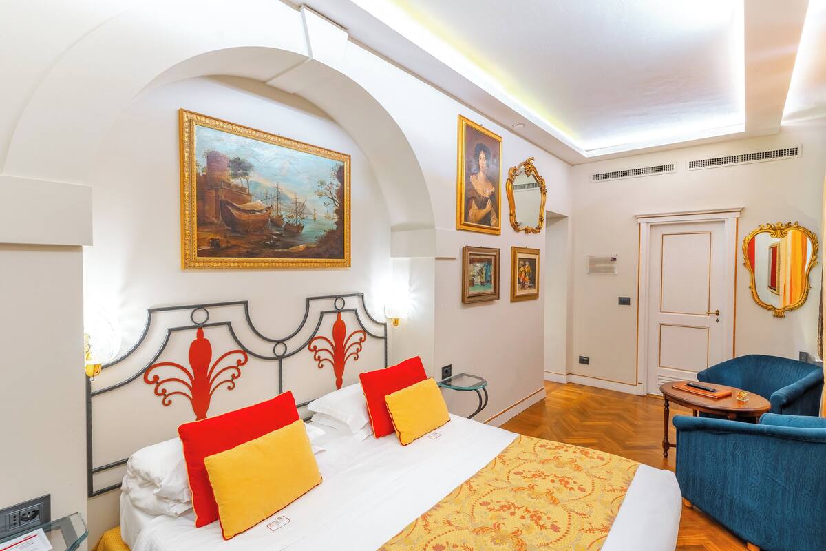 Une chambre d’hôtel avec un lit, un fauteuil bleu, une petite table et une porte.