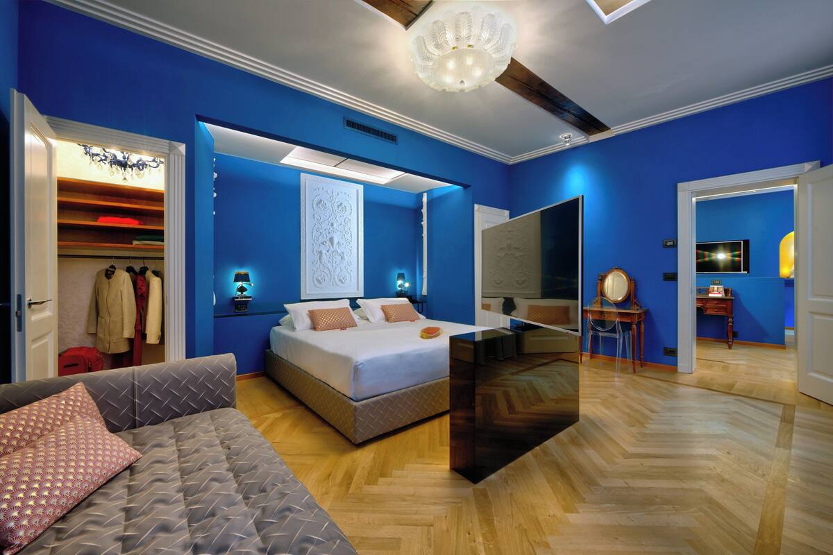 Ein modernes Schlafzimmer mit Bett, Sofa, Schreibtisch und Kleiderschrank.