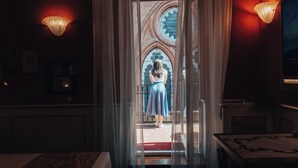 Une chambre d’hôtel avec une grande fenêtre, un lit, une table et un téléviseur fixé au mur.