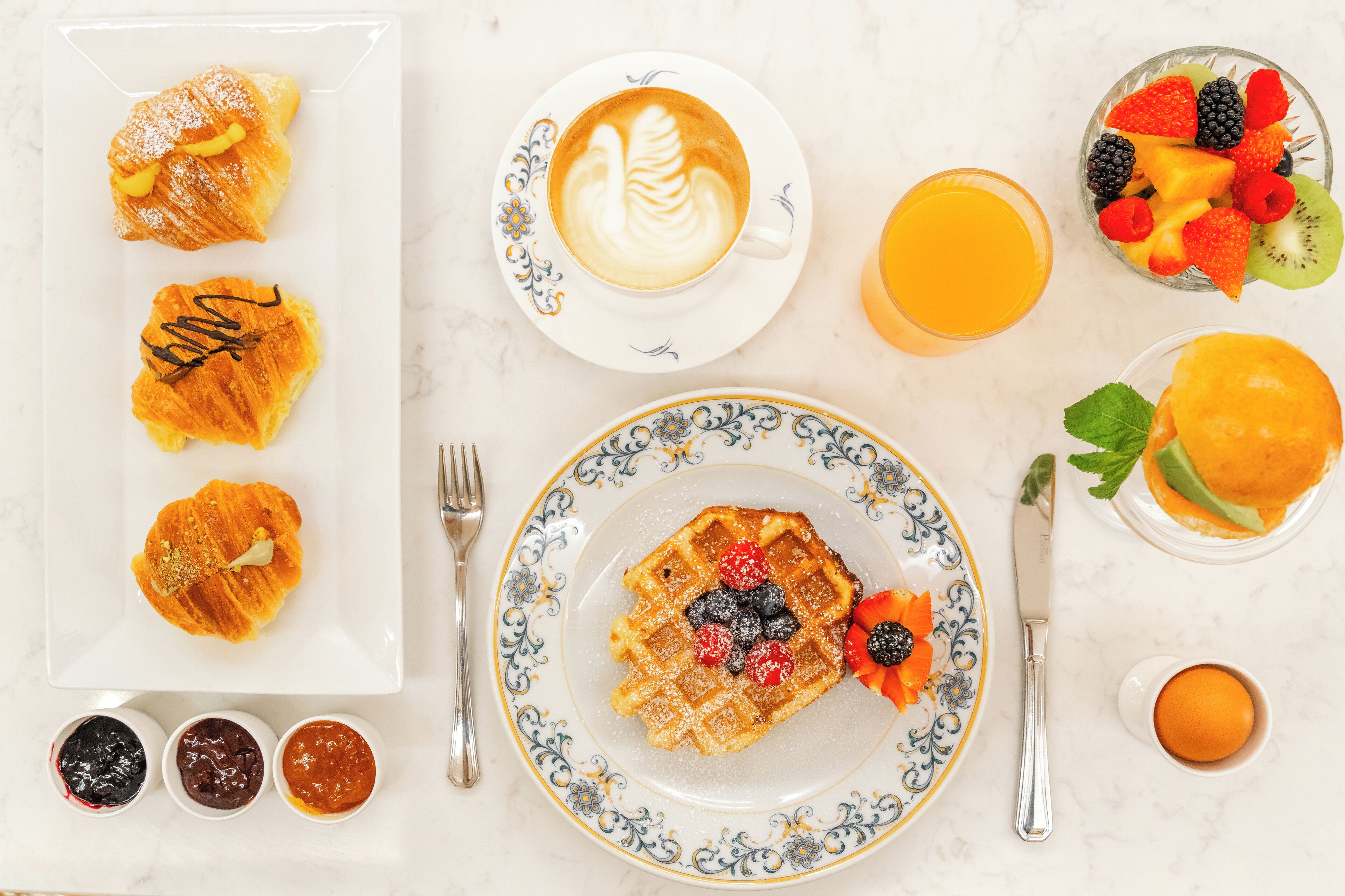 Desayuno con pasteles, café, fruta y jugo.
