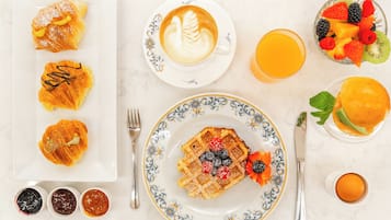 Desayuno con pasteles, café, fruta y jugo.