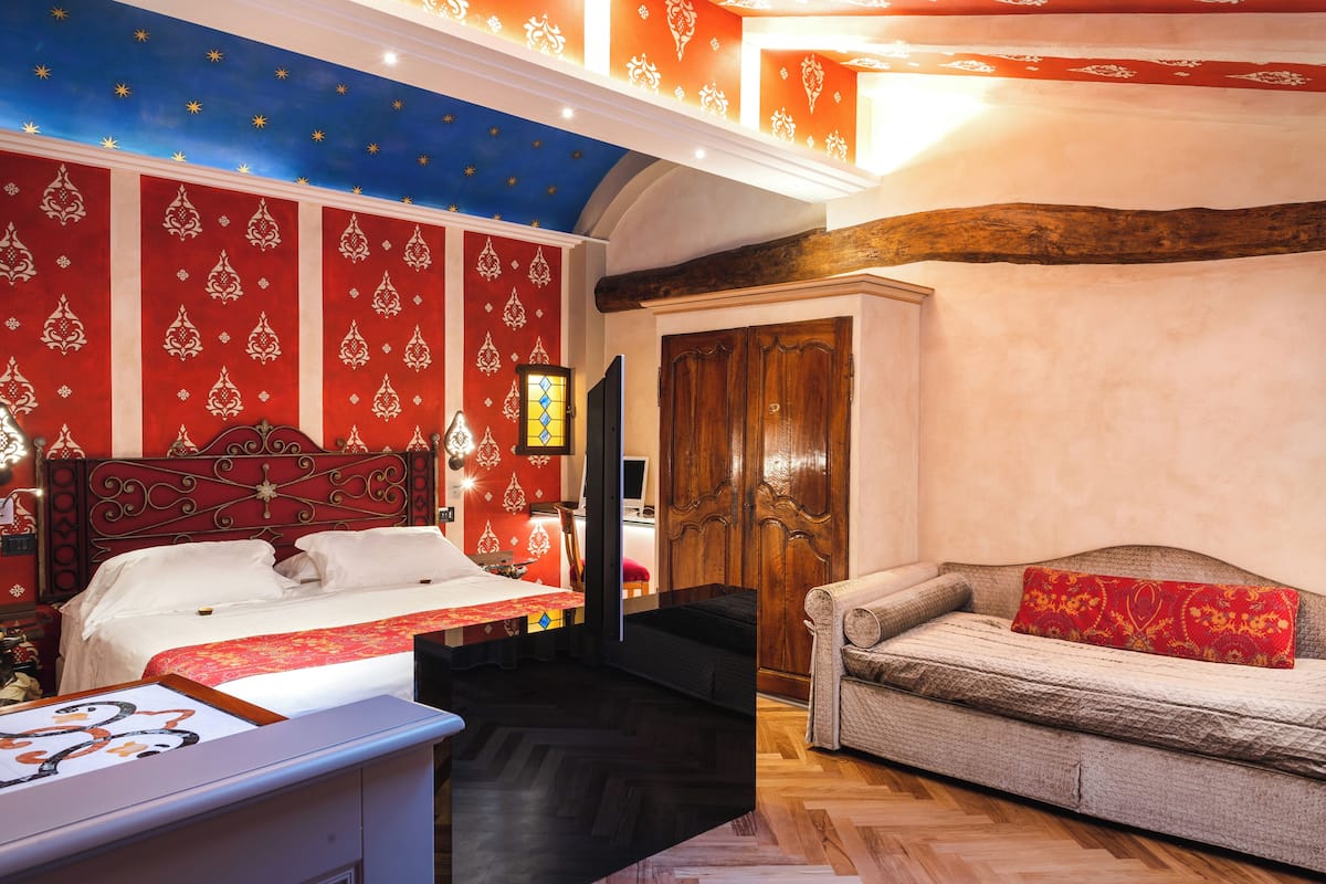 Une pièce comprenant un lit, un canapé, une armoire en bois et un plafond décoré de motifs en forme d’étoiles.
