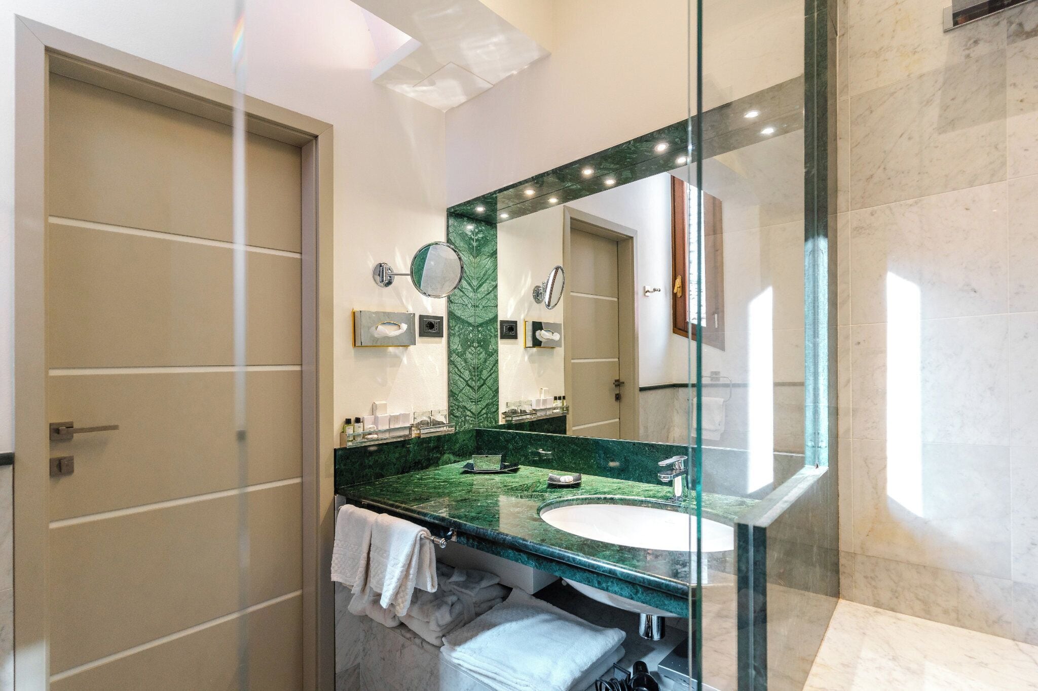 Een moderne badkamer met een grote spiegel, een groen marmeren aanrechtblad en een witte wastafel.