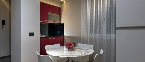 Una cocina moderna con armarios rojos, una mesa de mármol blanco y cuatro sillas blancas.