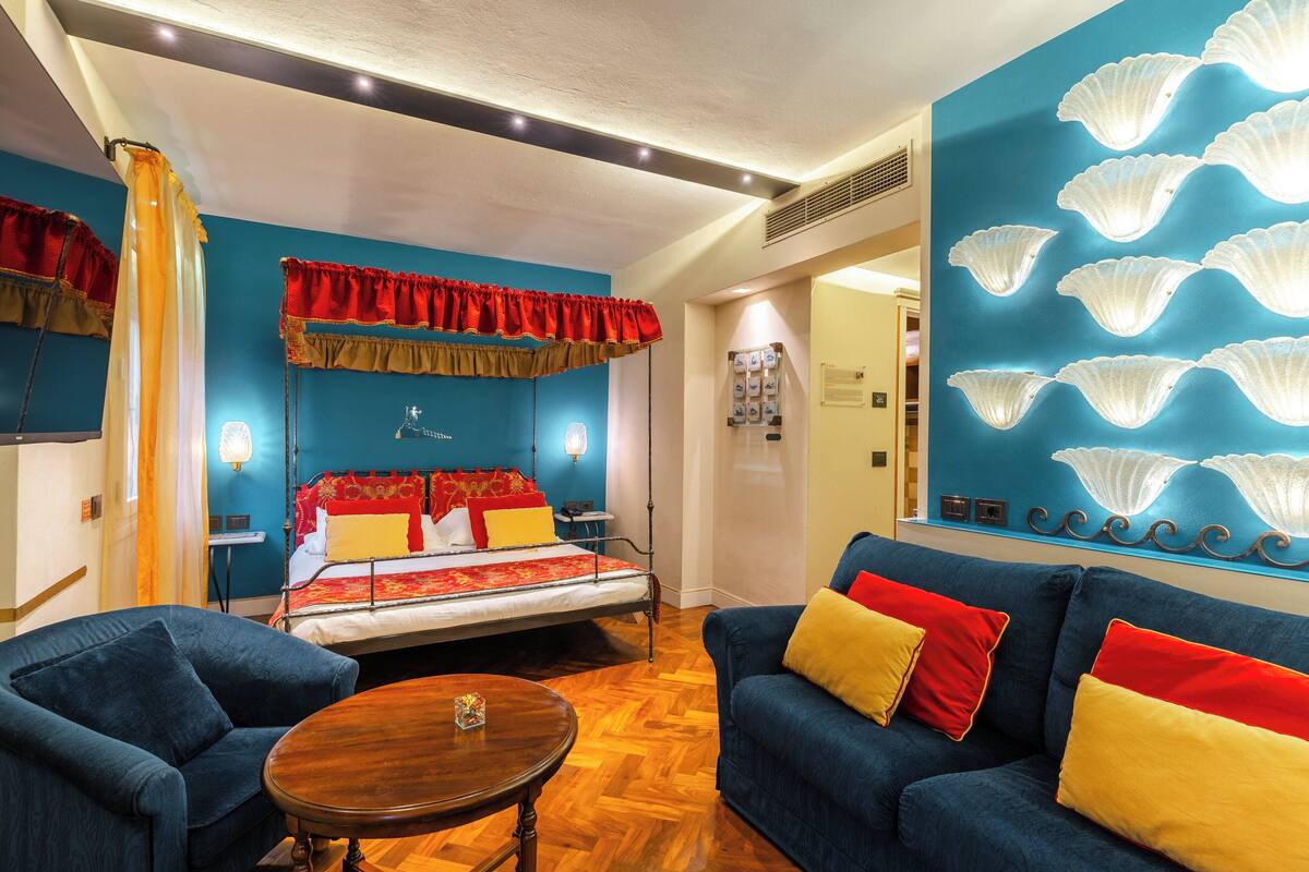 Une pièce avec un lit, un canapé bleu et une table ronde en bois.