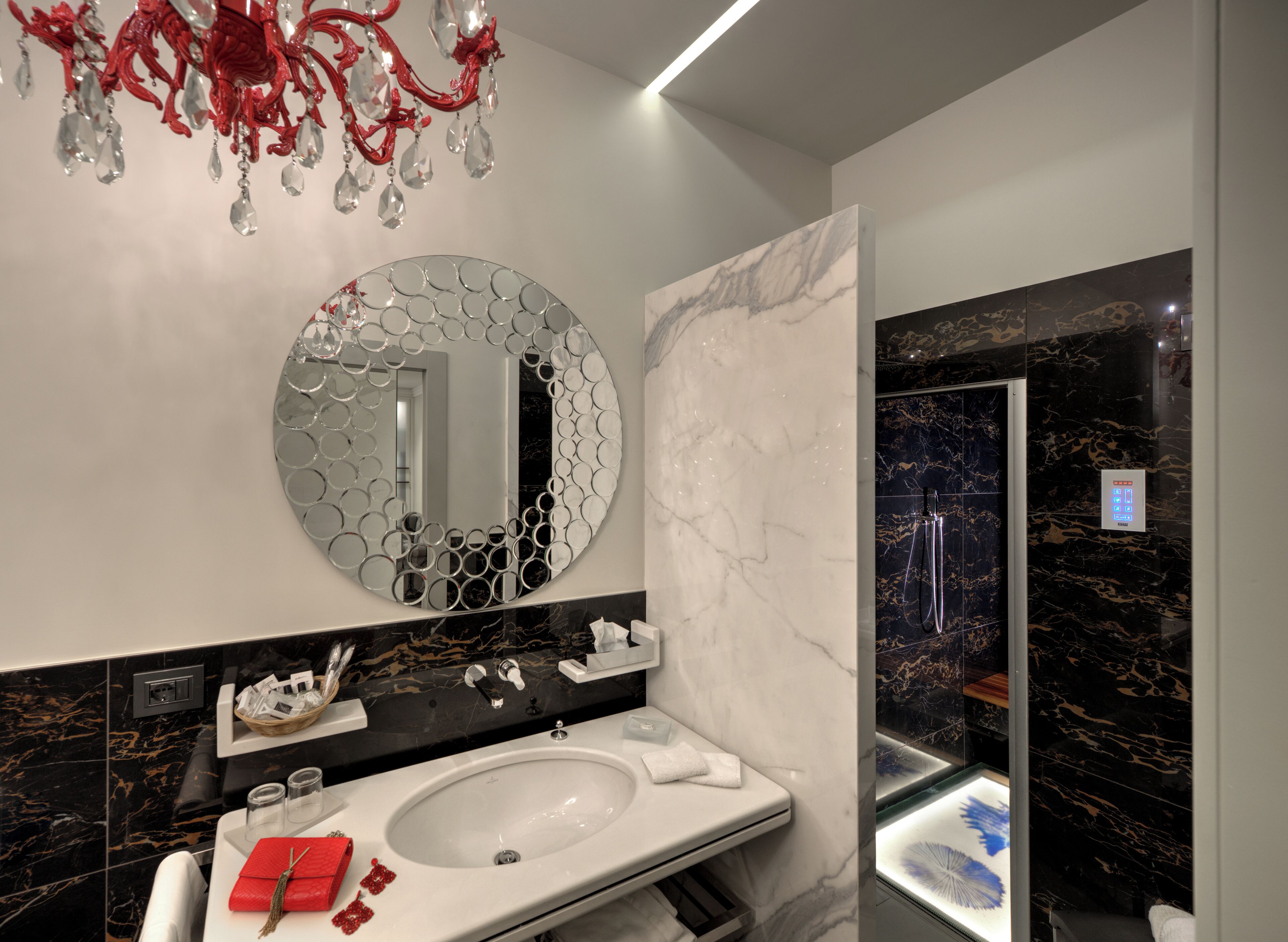 A modern bathroom with a round mirror, a white sink, and a shower area.