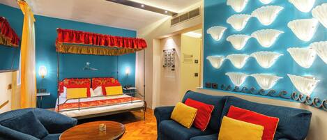A room with a bed, a blue sofa, and a wooden table.