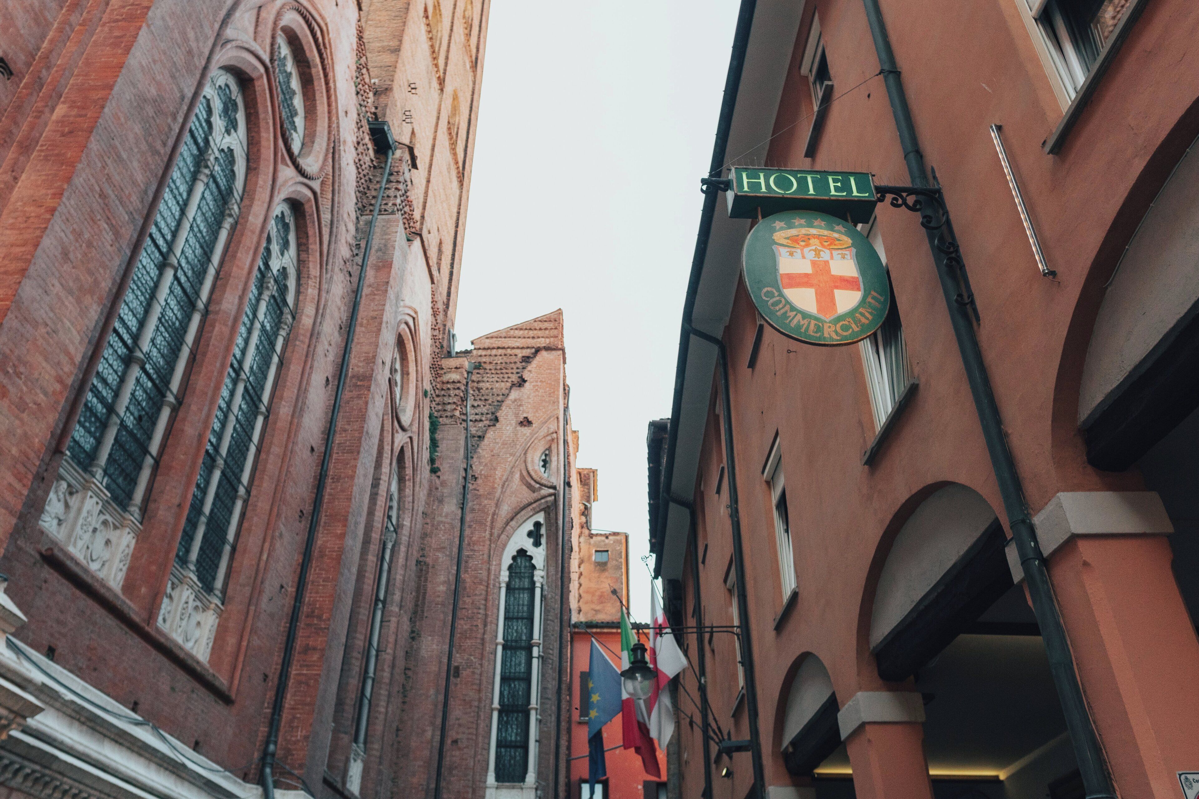 A narrow street with a hotel sign and flags.