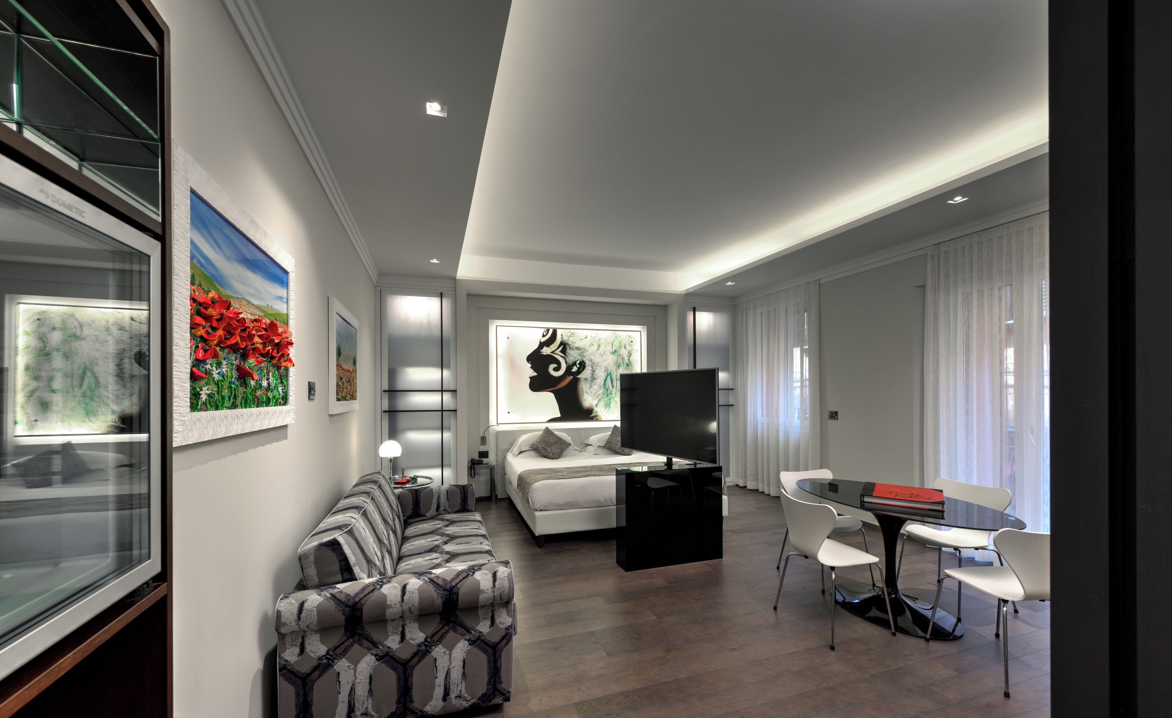 Un salon moderne comprenant un canapé, une table à manger avec des chaises, un téléviseur à écran plat et des œuvres d’art accrochées aux murs.