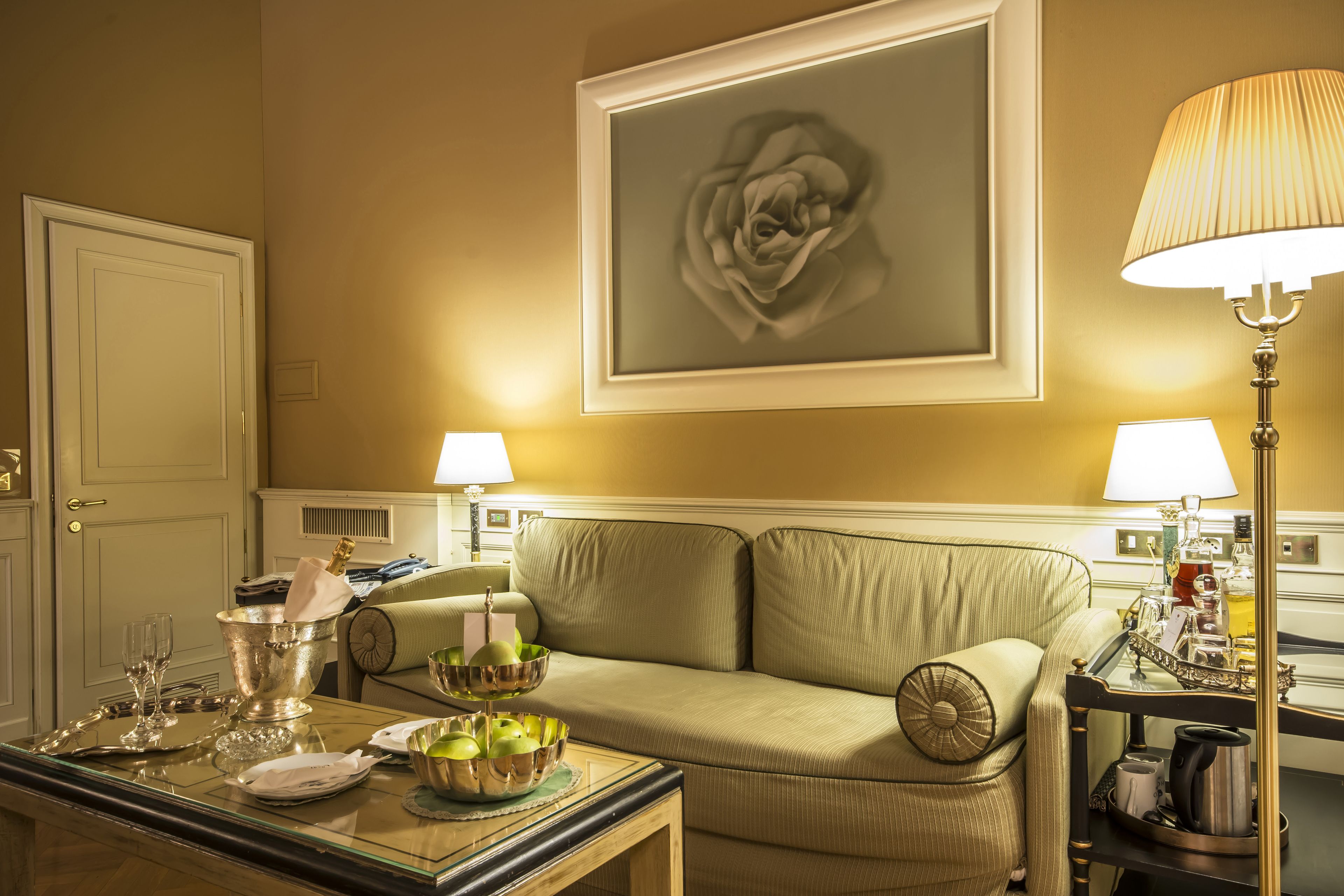 Una habitación luminosa con un sofá verde, una mesa de comedor con una lámpara y una obra de arte enmarcada en la pared.