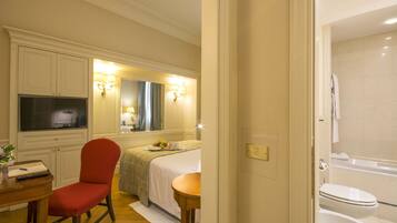 Hotelkamer met een bed, een bureau met stoel, een televisie, een badkamer met bad en toilet.