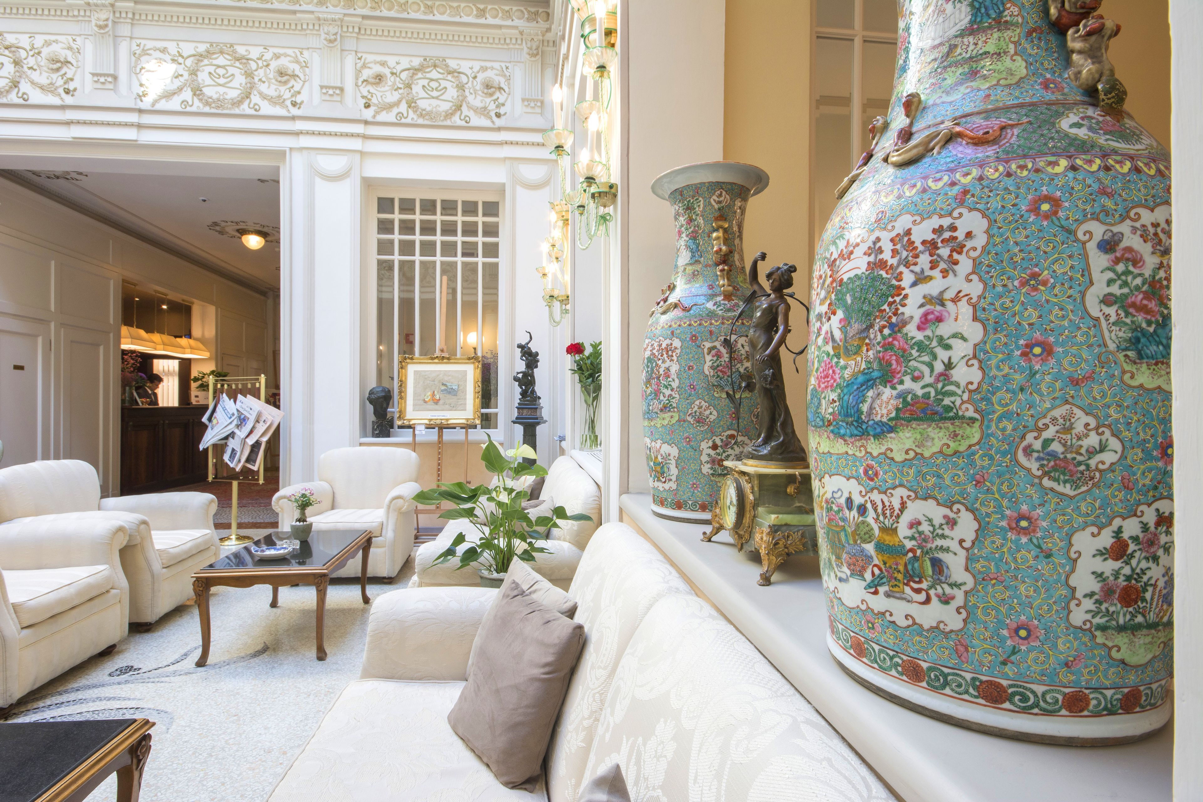 Uma sala de estar luxuosa com sofá, poltronas, mesa de centro e um grande vaso decorativo.