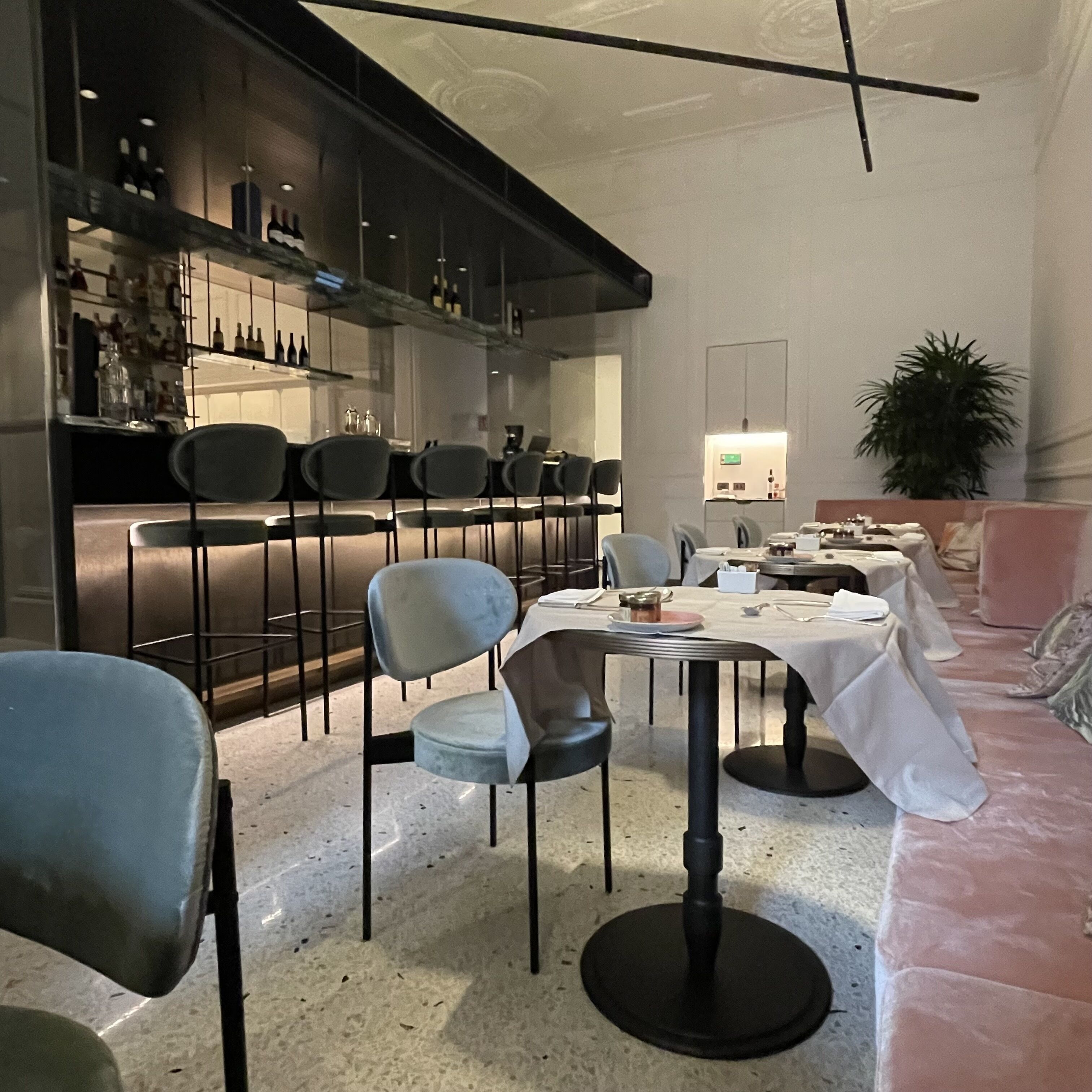 A modern dining area with a bar, multiple chairs, a round table, and a sofa.