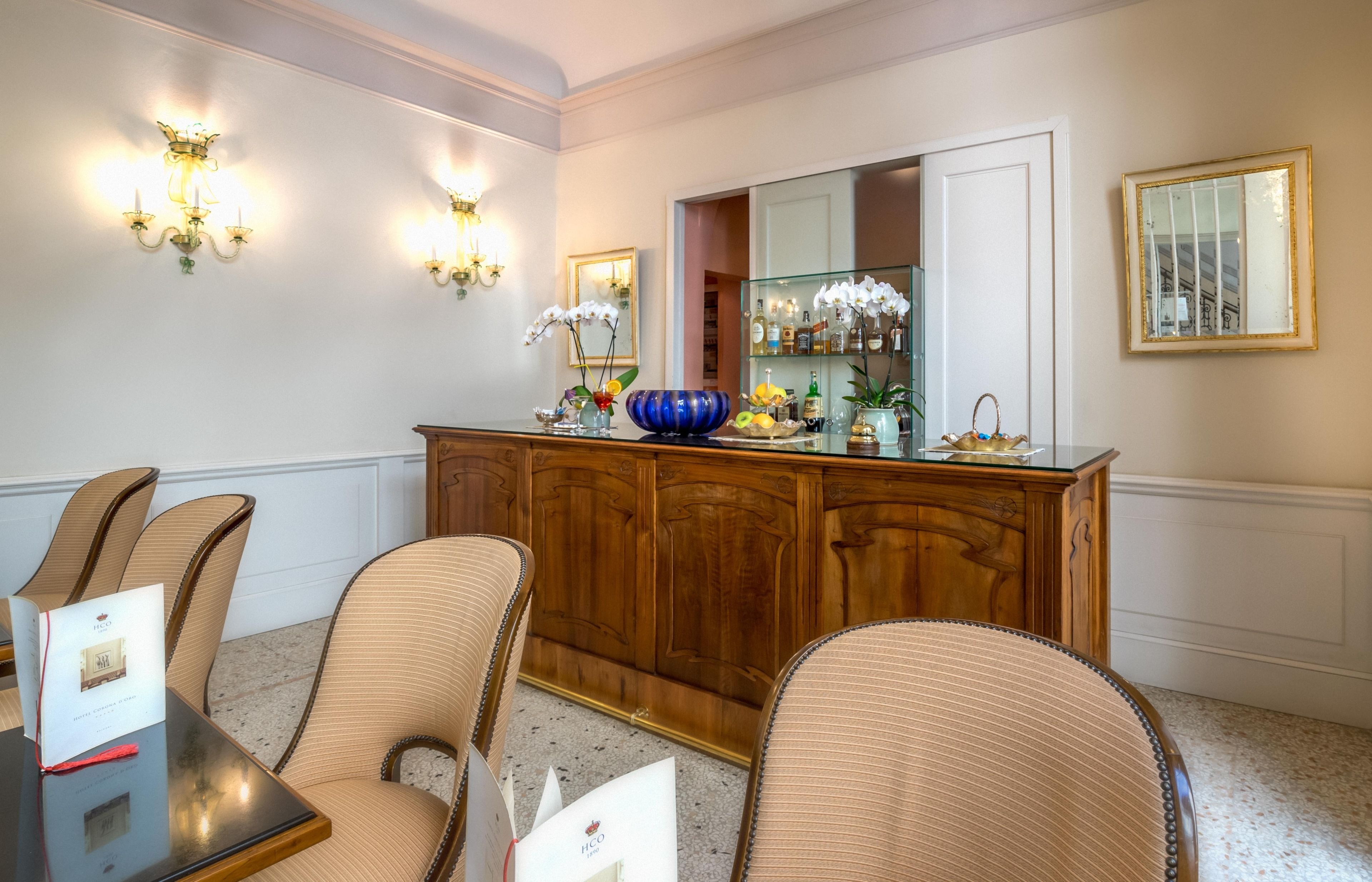 A dining area with a wooden buffet, wicker chairs, and wall sconces.