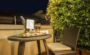 A wicker table with a metal pitcher, glasses, and a plate of food. - Hotel Corona d'Oro (Bologna)