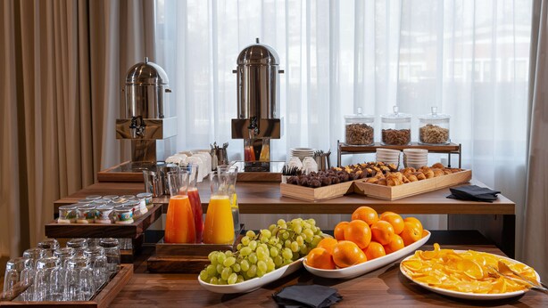 A breakfast buffet with various fruits, juices, and coffee makers. - DoubleTree by Hilton Brescia (Brescia)