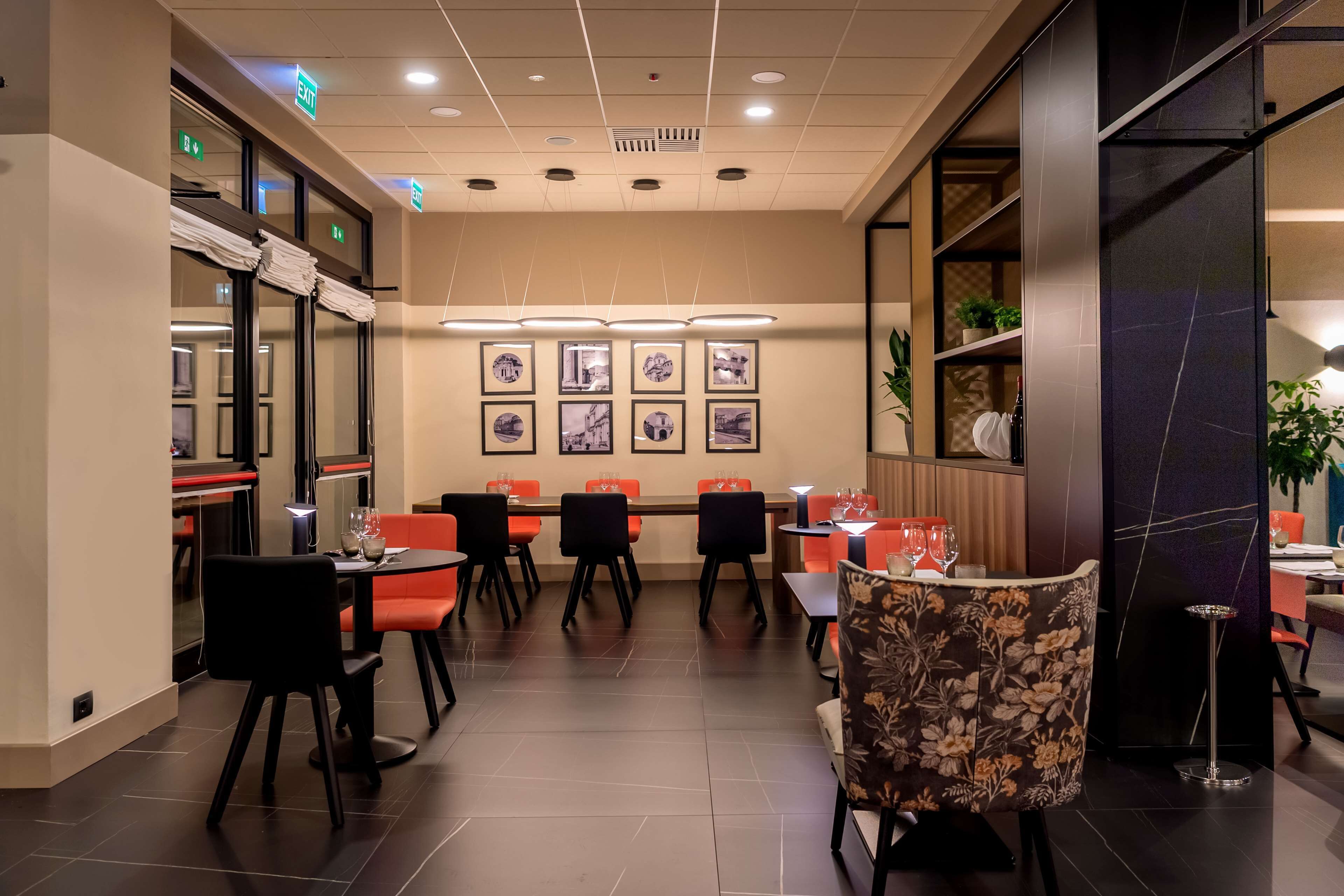 Un restaurante con varias mesas y sillas, un techo con iluminación empotrada y cuadros enmarcados en la pared.