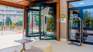 A hotel entrance with a glass door, a wheelchair ramp, and outdoor seating. - DoubleTree by Hilton Brescia (Brescia)