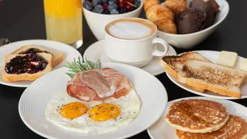 A breakfast table with toast, eggs, croissants, and a coffee cup.