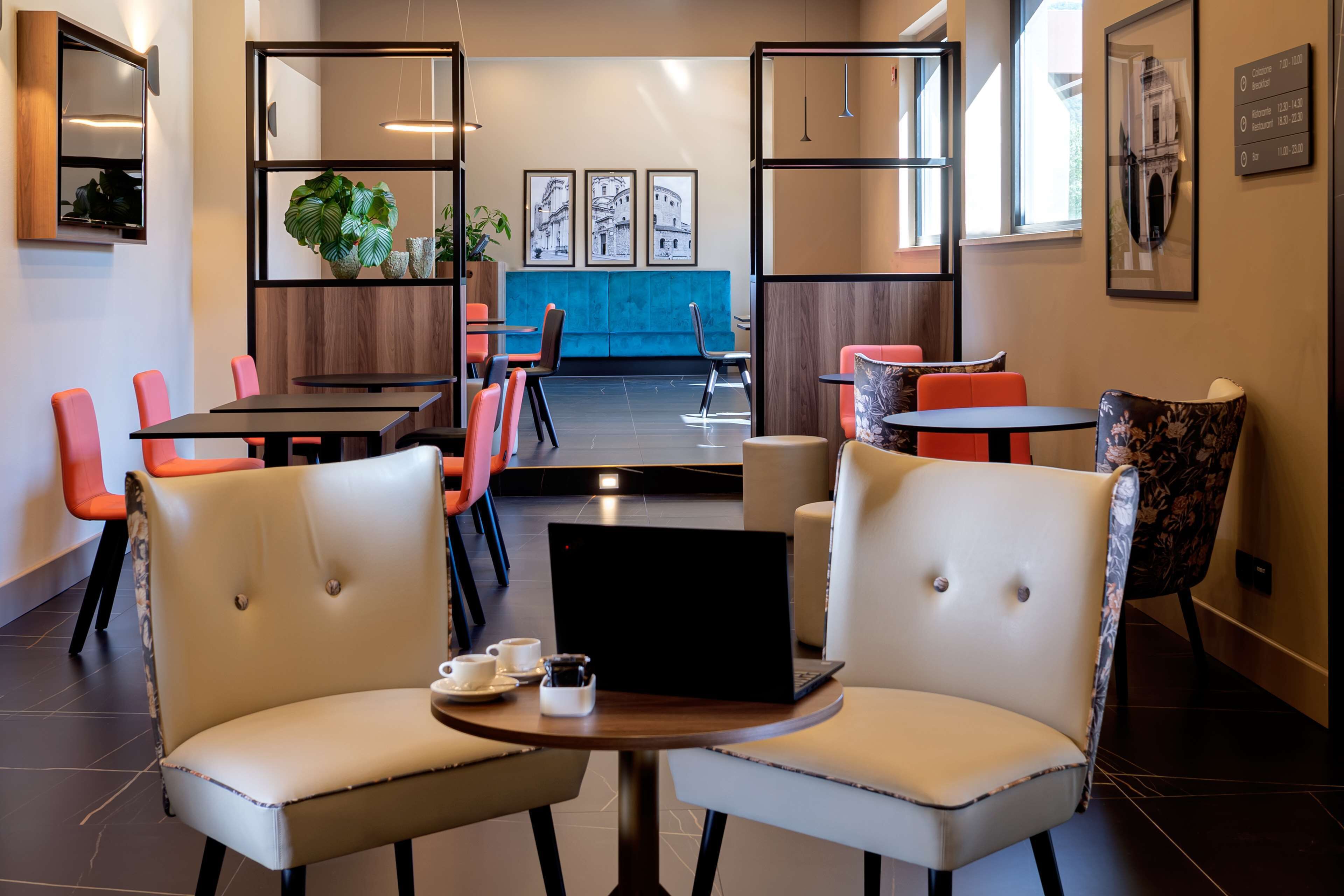 A modern cafe with a blue accent wall, multiple seating areas, and a laptop on a table.