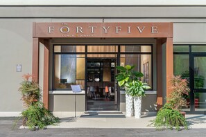 Exterior del restaurante The FortyFive, con una entrada moderna, zona de estar visible en el interior y dos macetas en la acera.