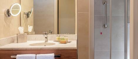 Un baño moderno con lavamanos, espejo y artículos de aseo.