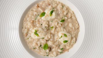 Een kom romige risotto met garnering.