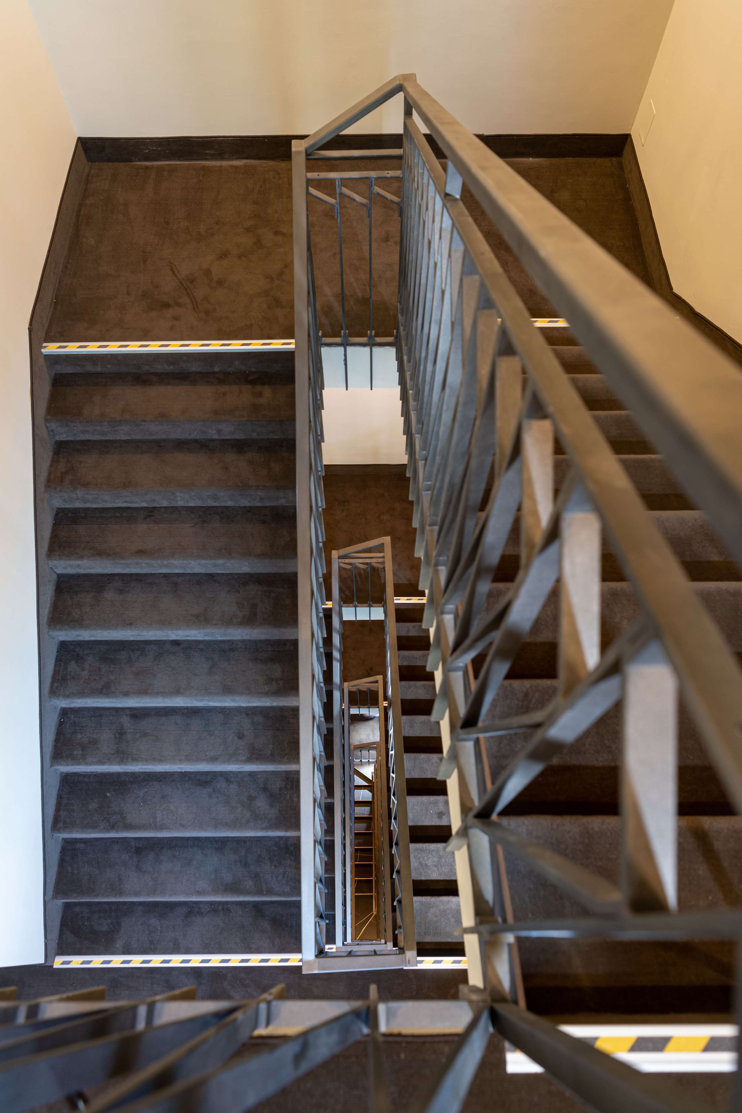 A modern staircase with metal railings and a carpeted floor.