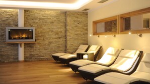 Un cuarto de spa con paredes de piedra, chimenea y sillones reclinables.