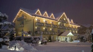 Un hotel de varios pisos con fachada amarilla, múltiples balcones y alrededores nevados.