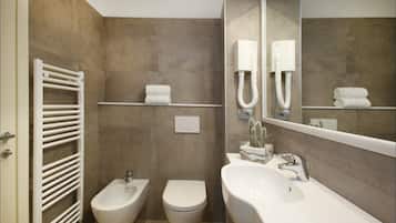 Et moderne badeværelse med bidét, toilet og en stor vask.