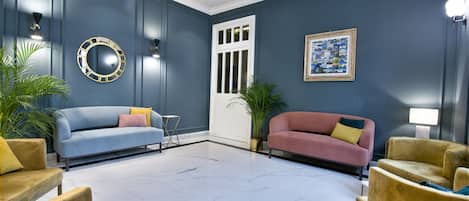 A room with a blue wall, two sofas, a small table, and a potted plant.