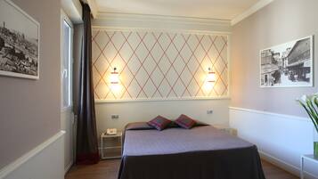 A hotel room with a bed, two bedside lamps, a nightstand, a telephone, and a picture on the wall.
