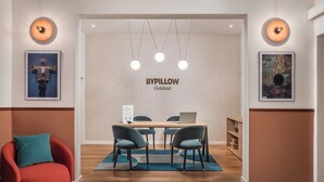 A modern hotel lobby with a wooden reception desk, a red armchair, and a blue rug. - BYPILLOW Goldoni (Florence)