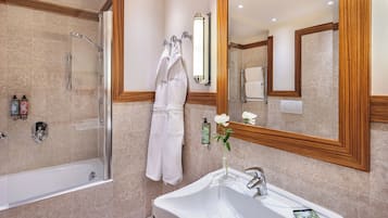 Un baño moderno con ducha de vidrio, un lavamanos blanco con un teléfono inteligente y un espejo con marco de madera.