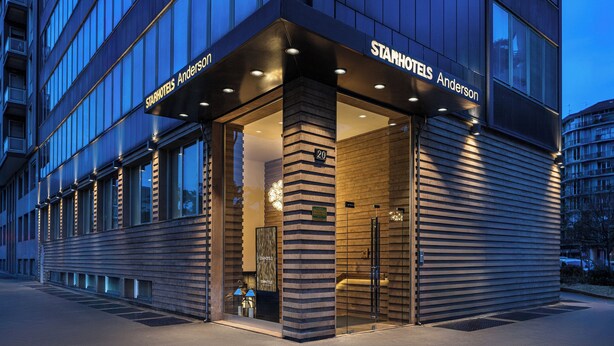 Una entrada moderna de hotel con un puerta de cristal, un cartel que dice "StarHotels Anderson" y el número "20" en la pared.