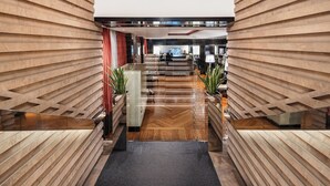 Un moderno vestíbulo de hotel con un diseño de pared de listones de madera, una recepción y plantas en macetas.