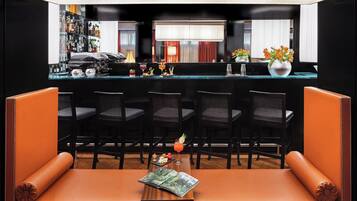 A bar area with a counter, bar stools, and a seating area with a sofa and chairs.