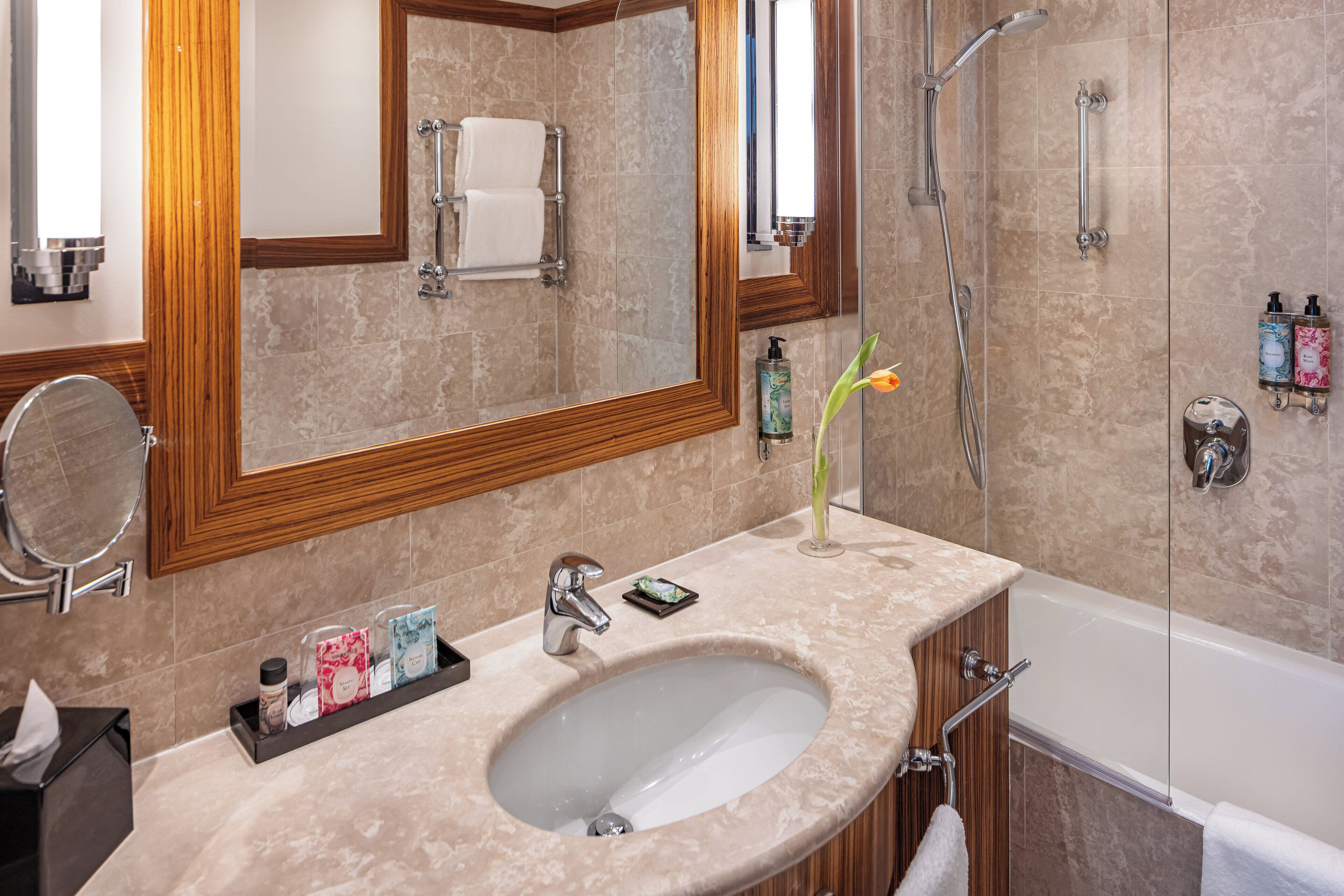A bathroom with a large mirror, a sink, a shower, and a bathtub.