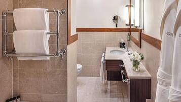 A modern bathroom with a bathtub, a vanity with a mirror, and a towel rack.