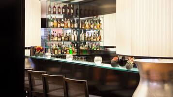 A bar area with a glass display case filled with various bottles, a few chairs, and a large vase.