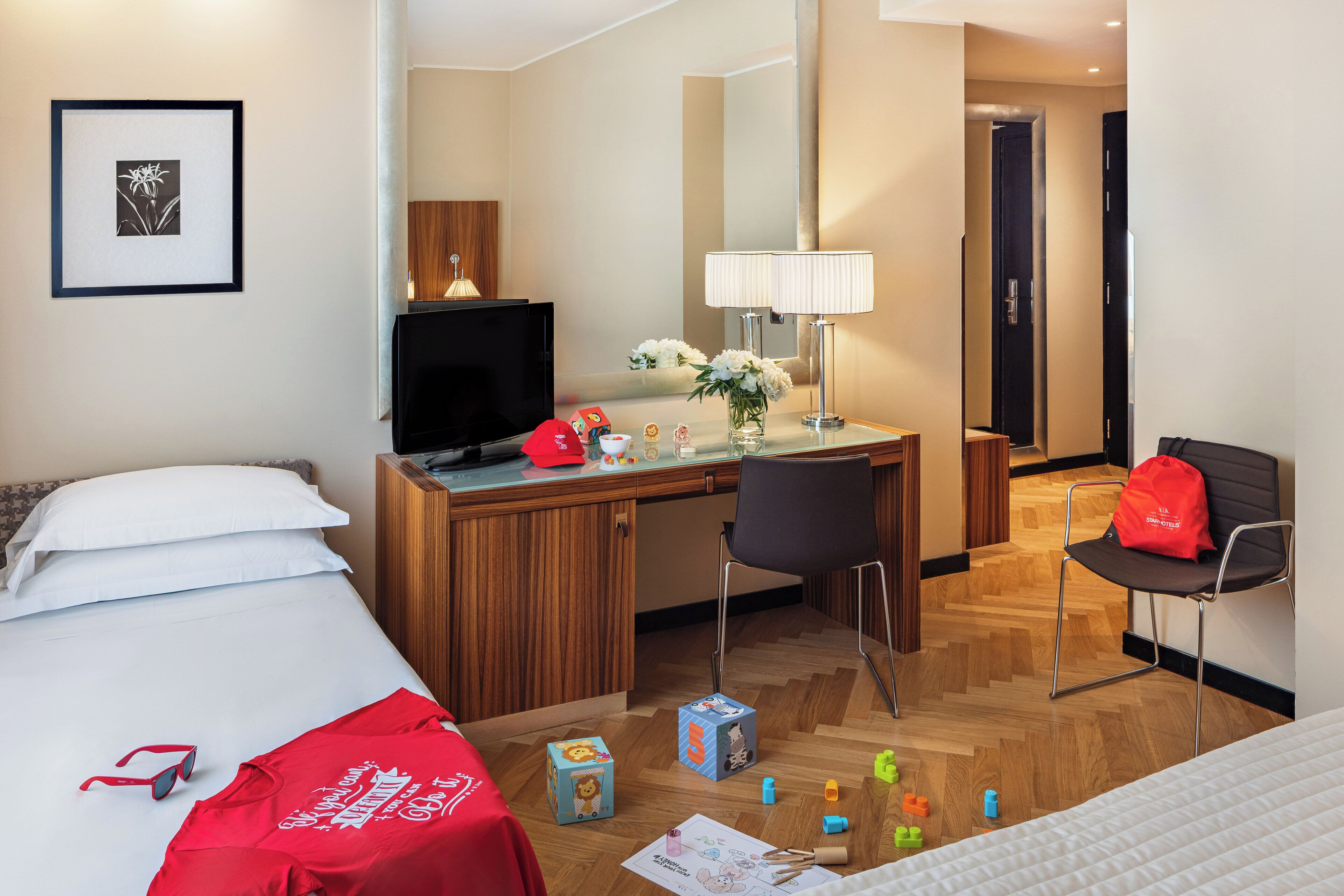 Habitación de hotel con cama, escritorio, silla y televisor.