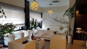 Ein modernes Wohnzimmer mit weißen Sofas, einem Couchtisch und Topfpflanzen.